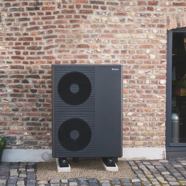 A aroTHERM plus heat pump outside of a red brick house