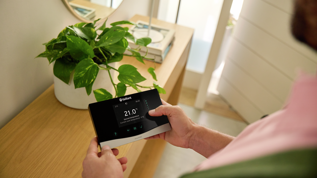 person holding a Vaillant heating control in their hands