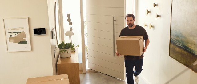 man carrying a cardboard box walking through a large door.