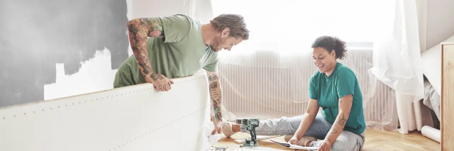 In a comfortable room, a man and woman are working together on a putting up a bed, creating a productive and intimate workspace.