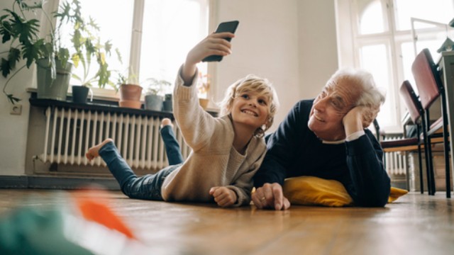 a young boy and older man taking a selfie on the floor