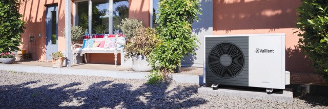 a heat pump outside a red house