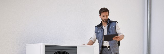 man with hand on top of the heat pump