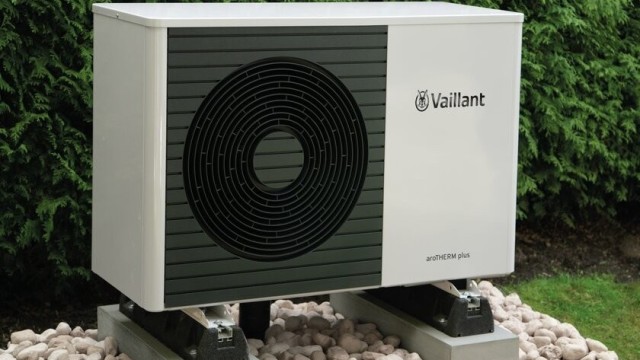 aroTHERM plys heat pump unit in front of a bush.