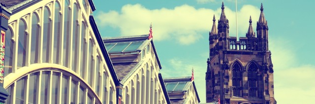 Stockport Old Market Hall with huge glass windows and old church with a clock in the middle