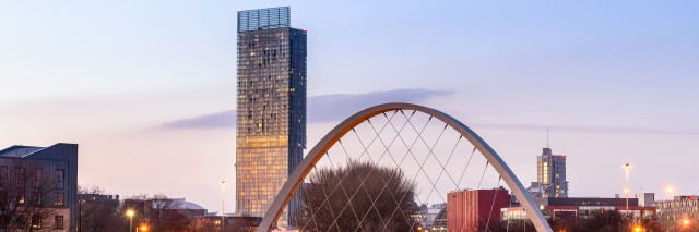 Sunset skyline of Manchester with a bridge and tall building in the background