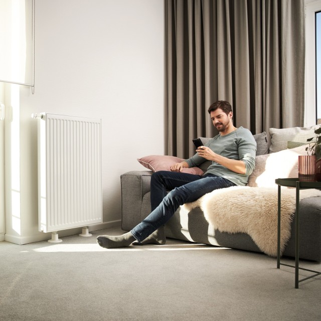 Photo of male homeowner sat on sofa next to radiator