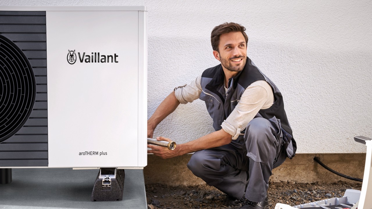Man carrying out installation work on a Vaillant heat pump unit.