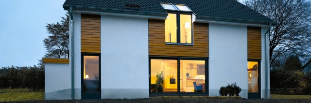 new build property with the lights on through the window