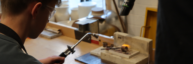 Person holding a blow torch in a workshop.