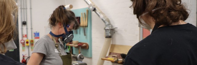 a group of students wearing a masks in a workshop style room