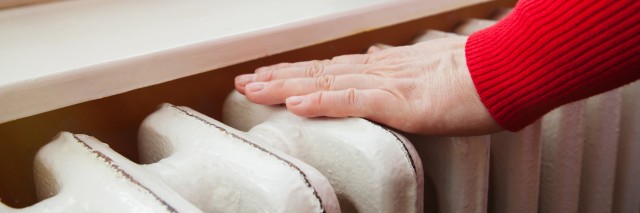 top of a radiator with a hand on the top and a mug on the shelf