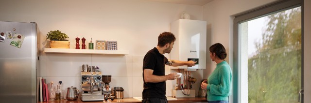 two people looking at a boiler in a kitchen
