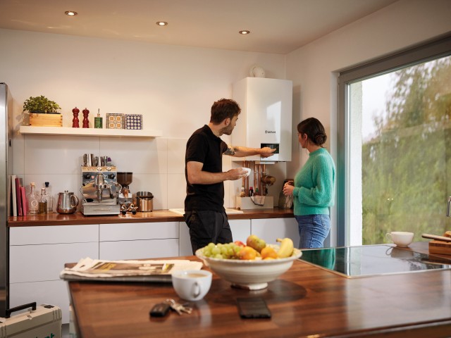 installer demonstrating a boiler to a woman in her kitchen