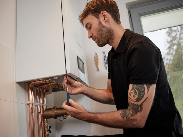 installer carrying out work underneath a boiler