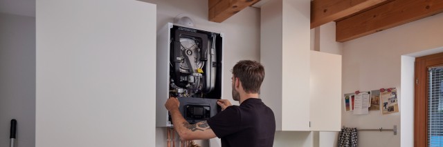 Installer carrying out work on a boiler in a laundry room