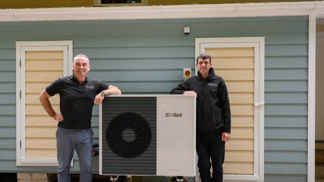 two installers leaning on a heat pump 