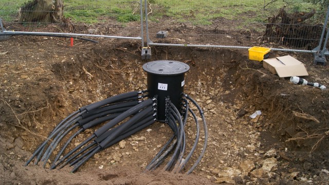 a black cylinder with some black pipes in the ground