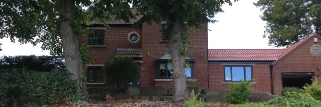 picture of a brick house with stone walls and trees