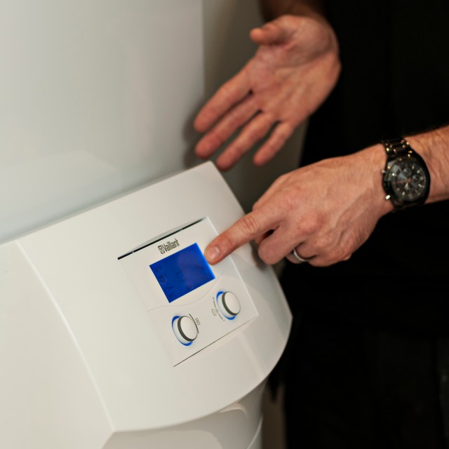 heat pump interface with a man with a watch on his wrist pressing a button