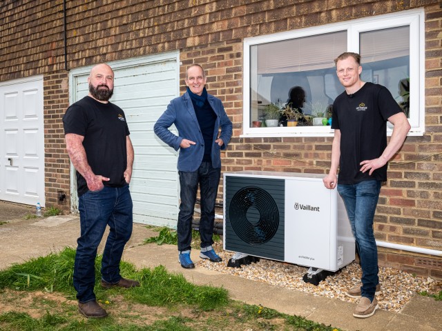 three people standing around a heat pump