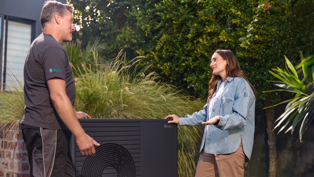 Two men working together on a heat pump, showcasing their skills and cooperation in a technical installation process.