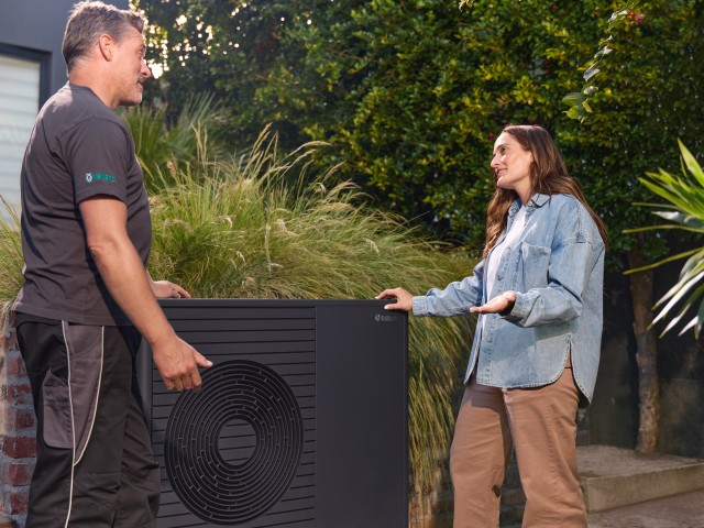 an installer talking to a homeowner in front of a Vaillant aroTHERM plus heat pump.