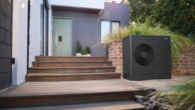 aroTHERM plus heat pump in the garden in front of a modern house.