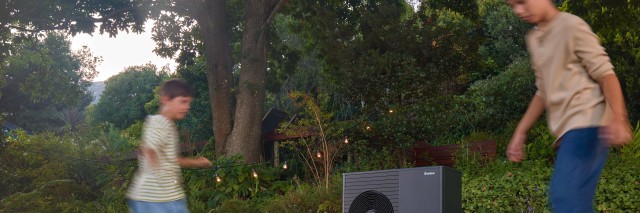 two children playing outside with a football in front of an aroTHERM plus heat pump.
