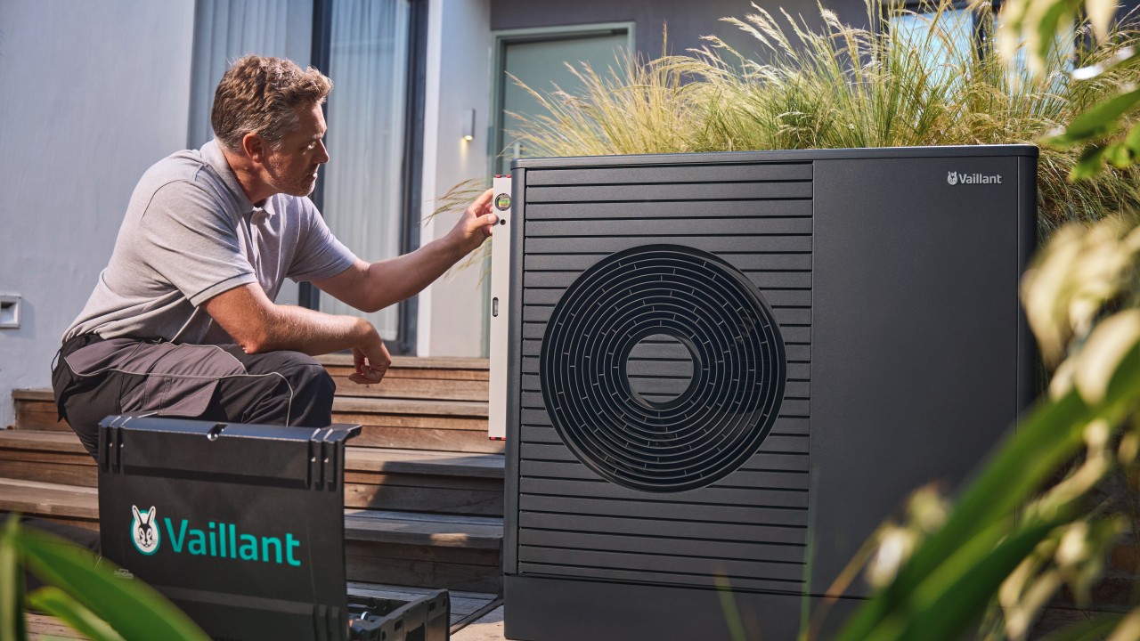 Man carrying out installation work on a Vaillant heat pump unit.
