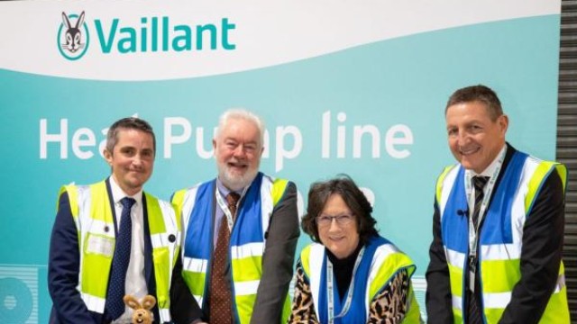 four people wearing a hi vis jacket leaning on a heat pump