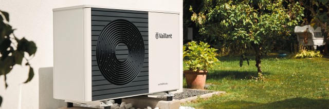 heat pump up against a white wall in a garden