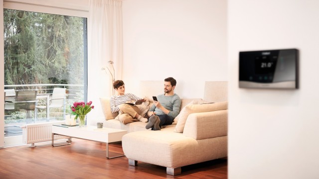 two people sat on a sofa and thermostat blurred out on the wall
