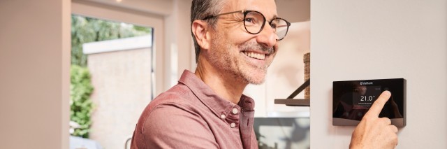 man touching thermostat on the wall