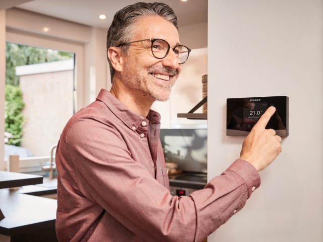 man turning down a thermostat on the wall