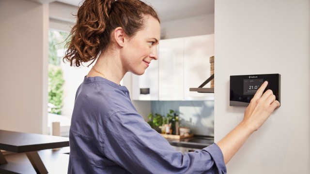woman turning down her thermostat on the wall