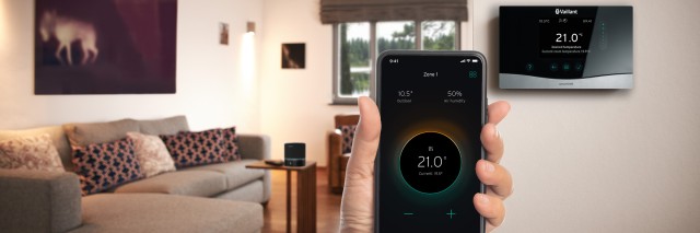 Someone holding a phone that displays myVAILLANT with a sensoHOME on the wall