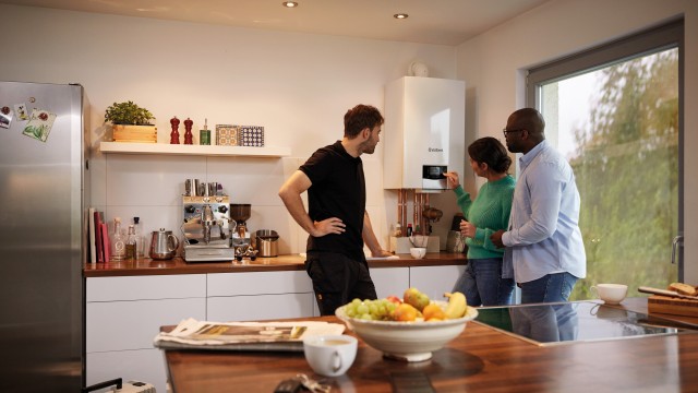 Couple in kitchen talking to Vaillant engineer with Vaillant ecoTEC plus in background