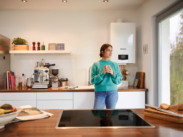 woman looking out the window in a kitchen with a boiler background