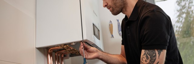 installer carrying out work underneath a boiler with copper pipes