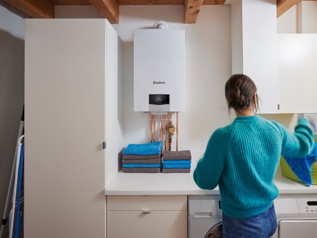 Image of a laundry room with a woman, back to camera, and a Vaillant ecoTEC plus in centre of frame