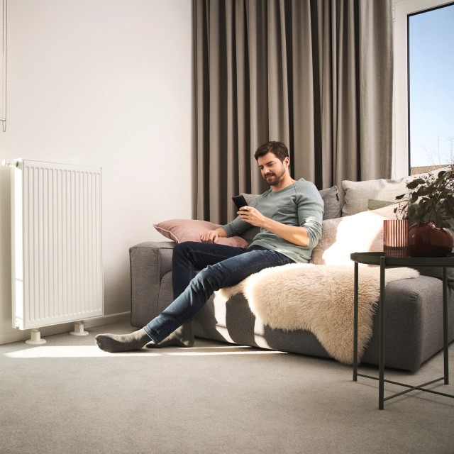 man sat on his sofa in the living room whilst on his phone