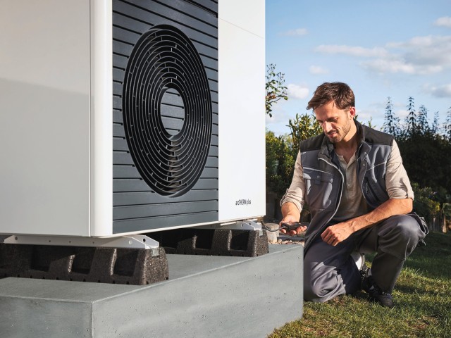 man doing work at the bottom of an air source heat pump.