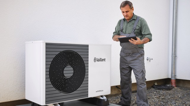 an installer looking at an ipad standing up with an aroTHERM air source heat pump on the ground