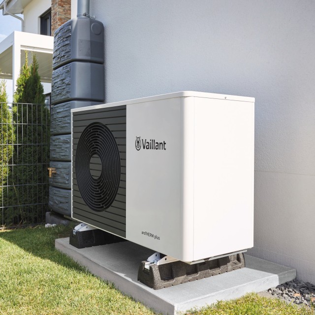 heat pump outside a white wall with grass
