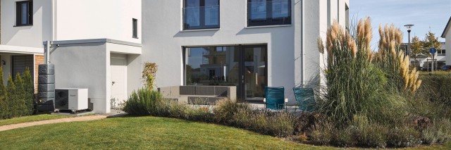A house featuring a white roof surrounded by a lush green lawn, showcasing a vibrant and inviting outdoor space.