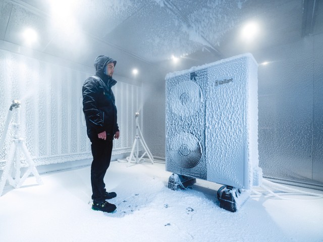 aroTHERM plus heat pump covered in snow and frost with a man looking at