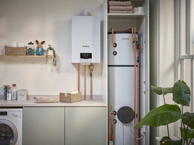 gas boiler on a kitchen wall and cylinder in a cupboard with other utility appliances. 