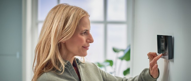 woman turning down a Vaillant thermostat on the wall.